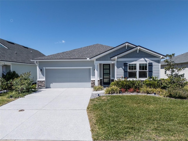 view of front facade featuring stone siding, a garage, driveway, and a front yard