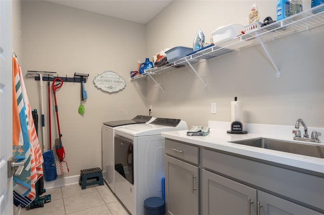 washroom featuring baseboards, washer and clothes dryer, light tile patterned floors, cabinet space, and a sink