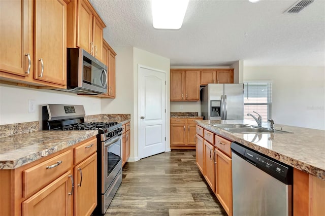 kitchen featuring visible vents, light countertops, appliances with stainless steel finishes, wood finished floors, and a sink