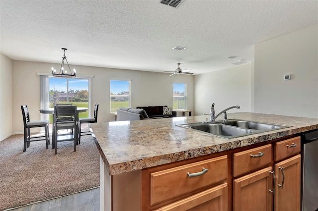 kitchen featuring a sink, decorative light fixtures, stainless steel dishwasher, open floor plan, and carpet flooring