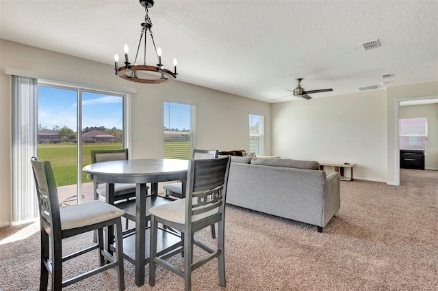 dining area with ceiling fan with notable chandelier, plenty of natural light, light colored carpet, and visible vents