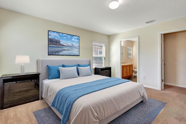 bedroom featuring baseboards, visible vents, a sink, light colored carpet, and connected bathroom