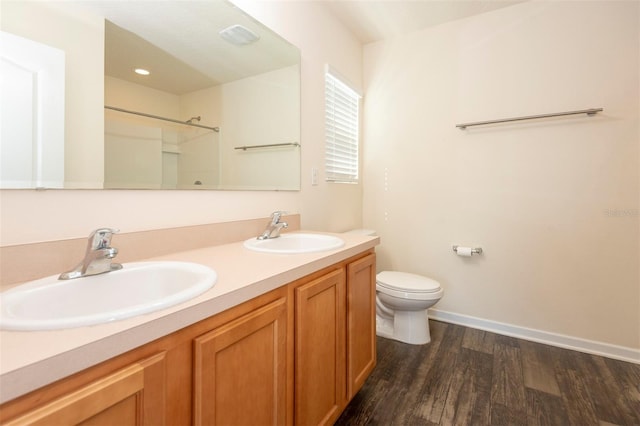 bathroom featuring a sink, toilet, wood finished floors, and double vanity