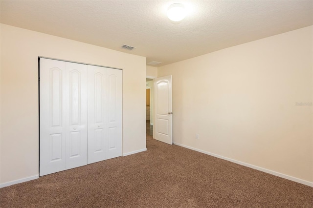 unfurnished bedroom with baseboards, visible vents, carpet floors, a closet, and a textured ceiling