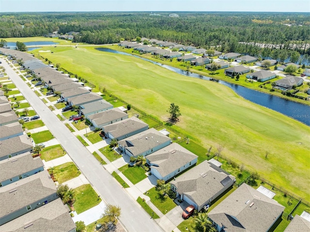 drone / aerial view featuring a residential view, a wooded view, view of golf course, and a water view