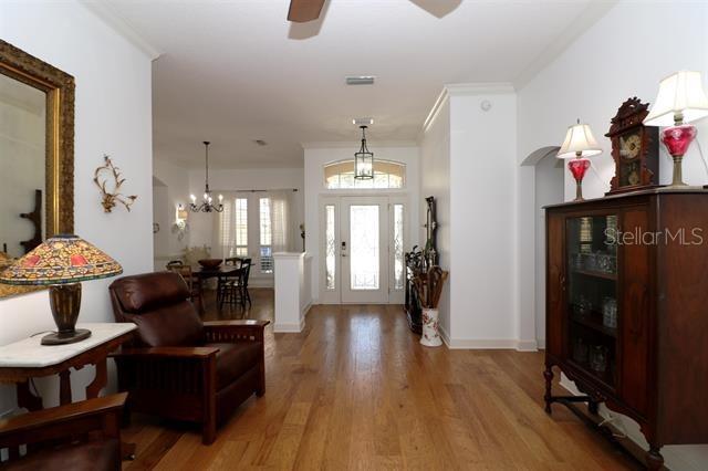 entryway featuring visible vents, light wood-style floors, arched walkways, and ornamental molding