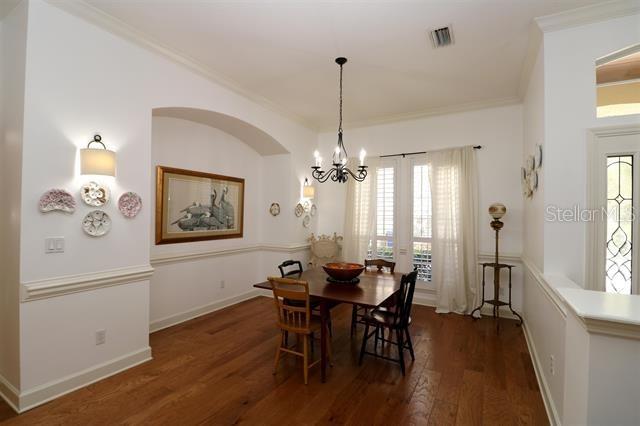 dining area featuring wood finished floors, baseboards, visible vents, ornamental molding, and a chandelier