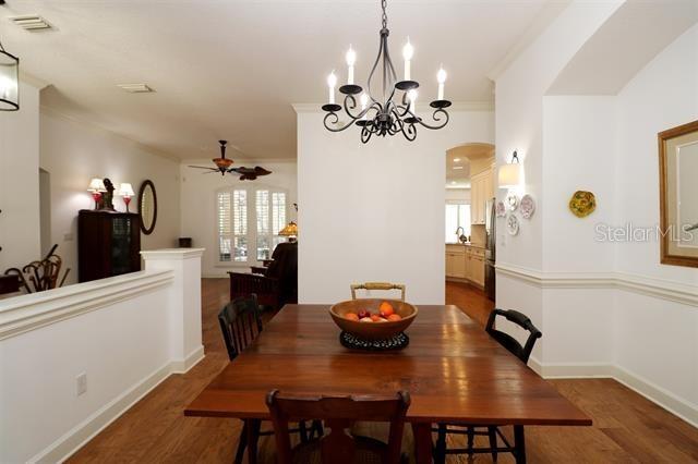 dining area featuring wood finished floors, baseboards, arched walkways, ceiling fan, and crown molding