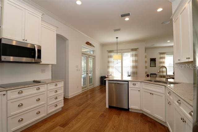 kitchen featuring a sink, a peninsula, white cabinets, and stainless steel appliances