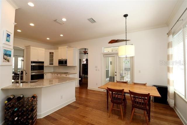 kitchen featuring visible vents, a sink, dark wood finished floors, stainless steel appliances, and glass insert cabinets