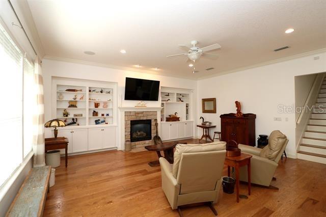 living area featuring stairs, light wood-style floors, visible vents, and ornamental molding