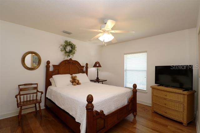 bedroom with visible vents, baseboards, ceiling fan, and wood finished floors