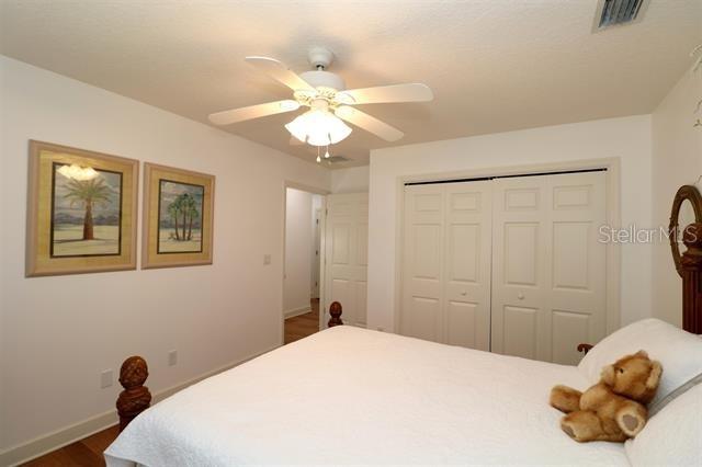 bedroom featuring visible vents, ceiling fan, baseboards, dark wood finished floors, and a closet