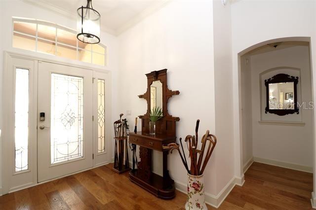 foyer with a wealth of natural light, ornamental molding, baseboards, and wood finished floors