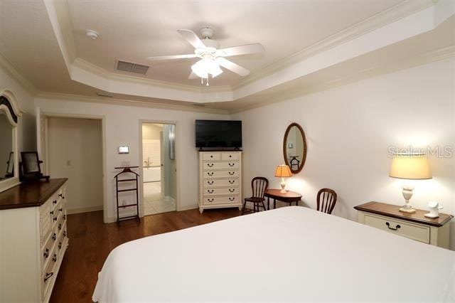 bedroom featuring dark wood-style floors, a raised ceiling, visible vents, and ornamental molding