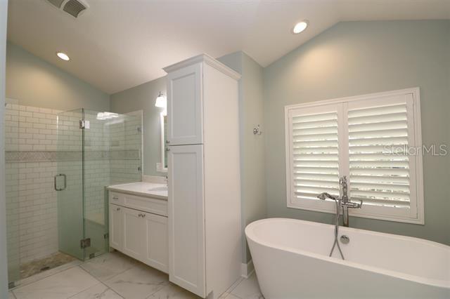 bathroom featuring visible vents, marble finish floor, a shower stall, lofted ceiling, and vanity