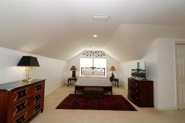 bedroom featuring light carpet, visible vents, baseboards, and vaulted ceiling