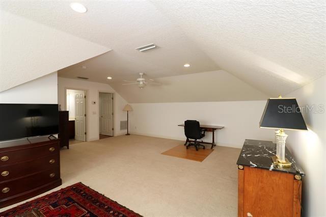 bonus room featuring lofted ceiling, carpet flooring, visible vents, and a textured ceiling