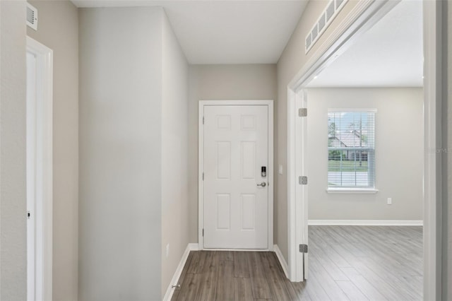 foyer entrance featuring visible vents, baseboards, and wood finished floors