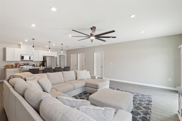 living room featuring wood finished floors, recessed lighting, visible vents, and baseboards