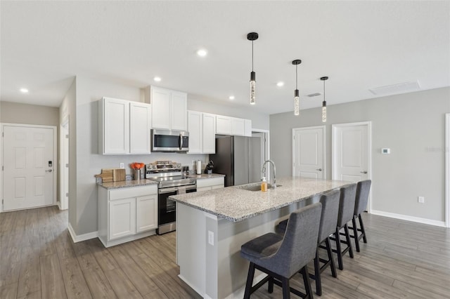 kitchen featuring light wood-style flooring, appliances with stainless steel finishes, an island with sink, and a sink