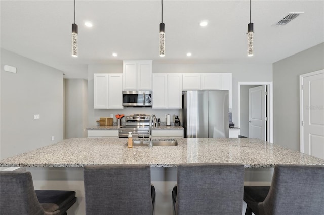 kitchen with visible vents, stainless steel appliances, a large island, white cabinetry, and a sink