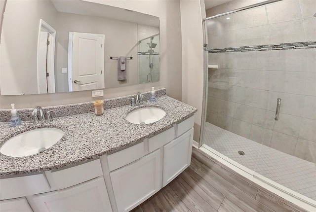 bathroom with a shower stall, double vanity, and a sink