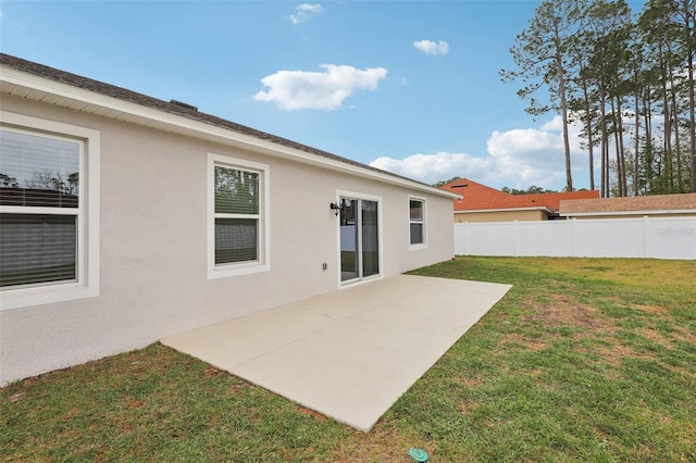 back of house featuring a patio area, stucco siding, a lawn, and fence