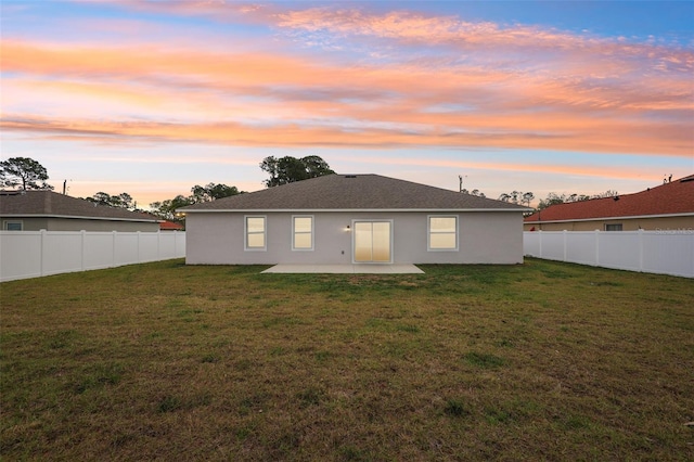 rear view of property featuring a yard, a patio, a fenced backyard, and stucco siding