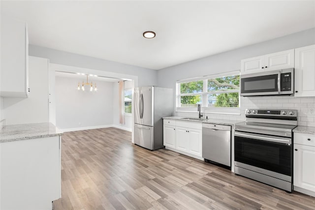 kitchen with decorative backsplash, stainless steel appliances, light wood-style floors, white cabinetry, and a sink