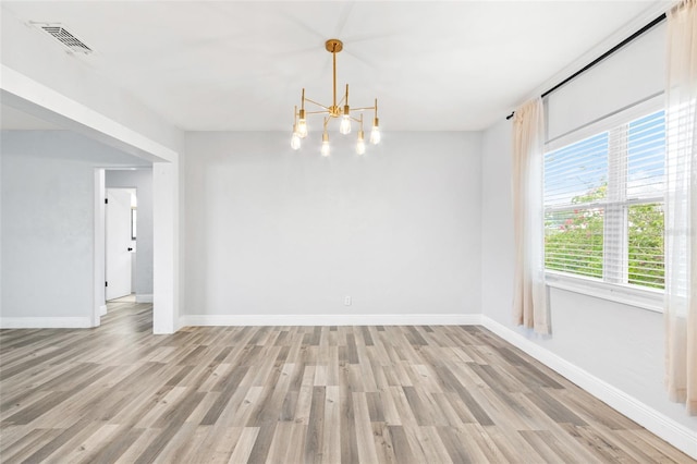 unfurnished room with light wood finished floors, visible vents, a notable chandelier, and baseboards