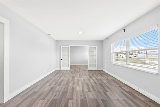 spare room with baseboards and wood finished floors