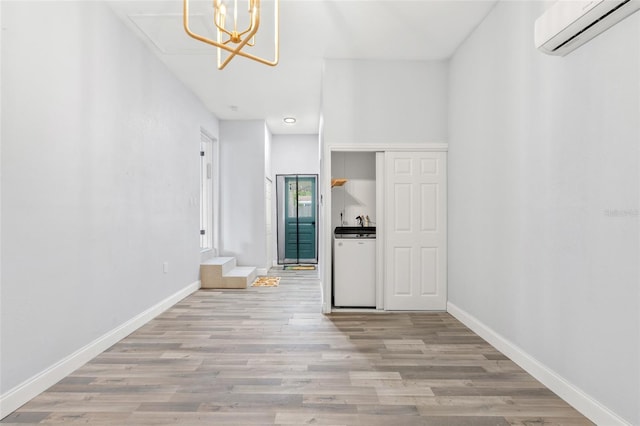 interior space with washer / clothes dryer, an AC wall unit, baseboards, and wood finished floors