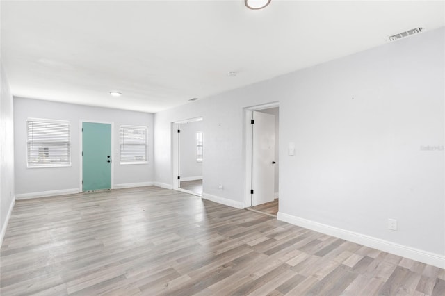 unfurnished living room with visible vents, plenty of natural light, baseboards, and light wood-style floors