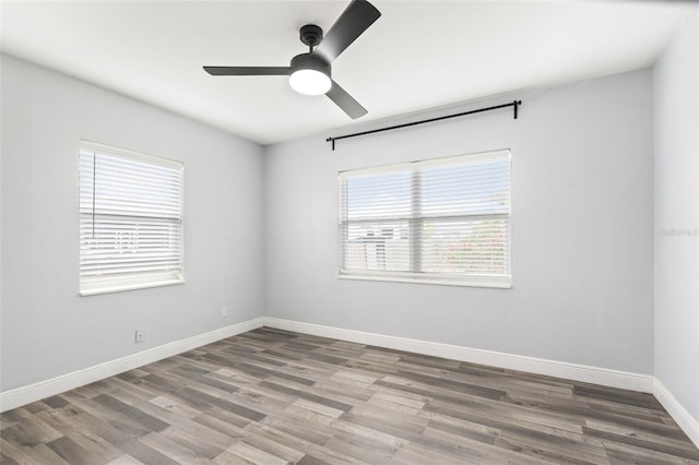 spare room featuring baseboards, wood finished floors, and a ceiling fan