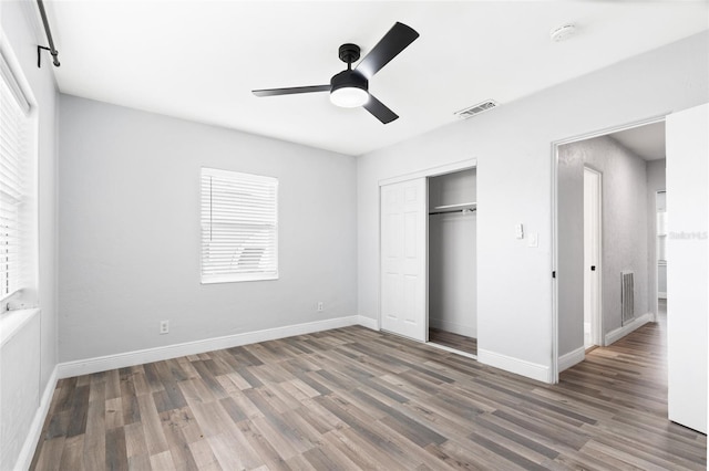 unfurnished bedroom featuring visible vents, wood finished floors, a closet, baseboards, and ceiling fan