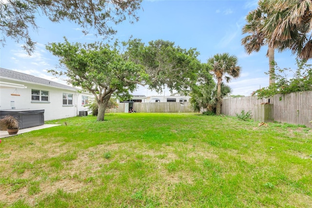 view of yard with central air condition unit, a hot tub, and fence