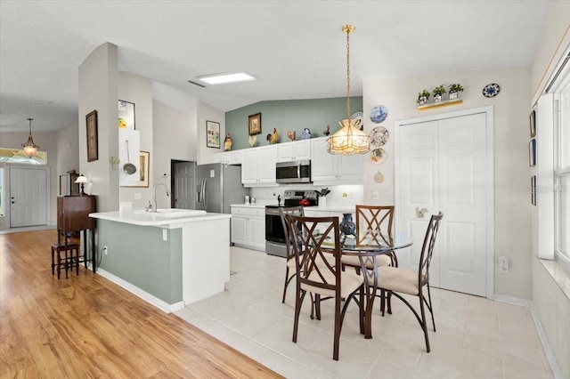 kitchen with a breakfast bar, white cabinetry, stainless steel appliances, a peninsula, and light countertops