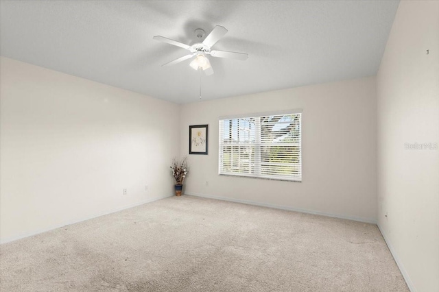 carpeted empty room with baseboards and ceiling fan