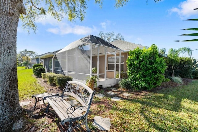 rear view of house featuring a lanai and a lawn