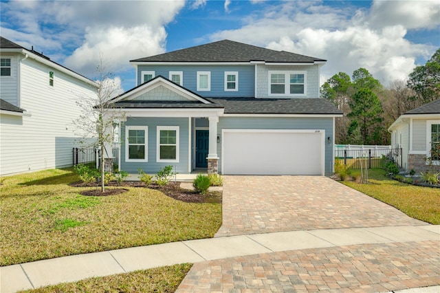 view of front of house featuring an attached garage, decorative driveway, a front lawn, and fence