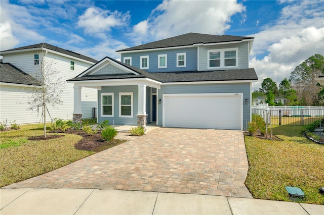 view of front of house with decorative driveway, an attached garage, a front yard, and fence