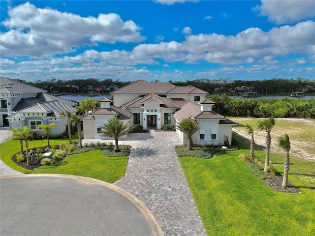 view of front of home with a residential view, stucco siding, decorative driveway, and a front yard