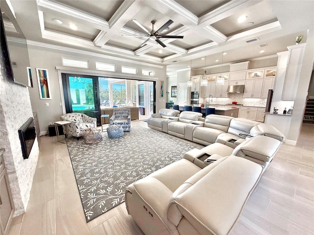 living area with visible vents, coffered ceiling, a fireplace, crown molding, and a towering ceiling