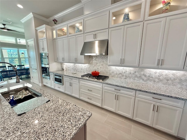 kitchen featuring under cabinet range hood, tasteful backsplash, appliances with stainless steel finishes, and ornamental molding