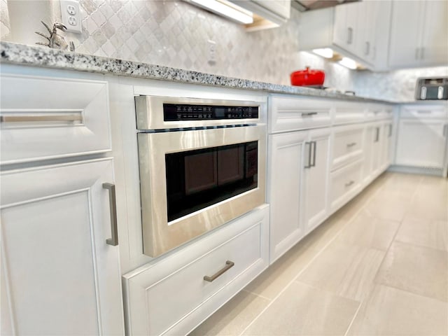 kitchen with light countertops, white cabinets, tasteful backsplash, and oven