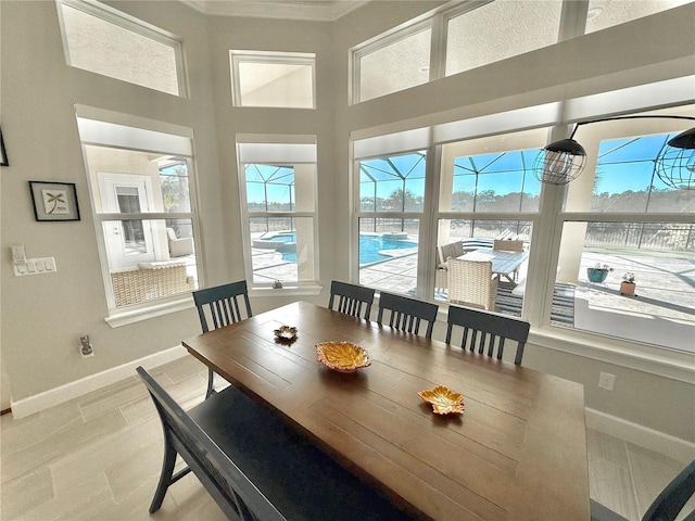 dining room featuring a towering ceiling, baseboards, and a sunroom