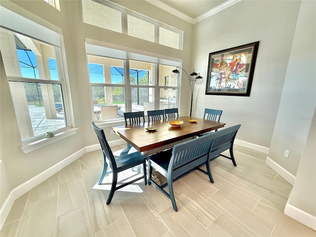 dining room with a high ceiling, baseboards, and ornamental molding