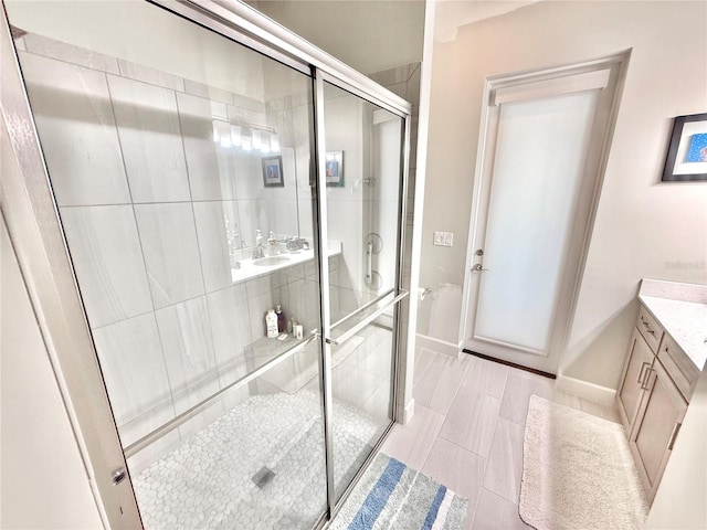 full bathroom featuring vanity, a shower stall, and baseboards