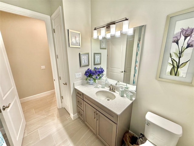 bathroom with baseboards, toilet, and vanity